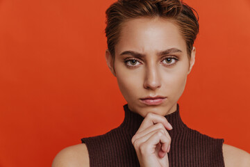 Portrait of young beautiful short-haired thoughtful serious woman touching chin