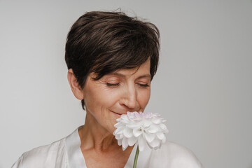 Obraz na płótnie Canvas Senior woman smelling flower isolated over white background