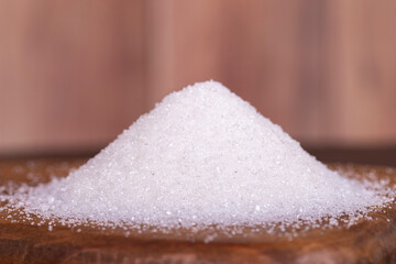 Granulated sugar. White refined sugar on wood background. Close up