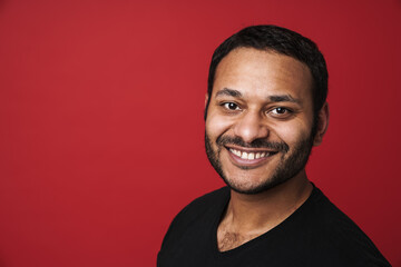 Obraz premium Indian man looking at camera and smiling isolated over red background