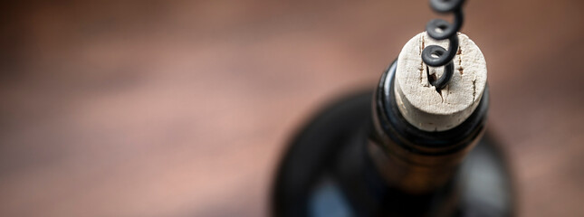 Bottle of wine, cork and corkscrew on wooden table background