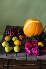 Autumn still life with seasonal fruits,flowers and vegetables on wooden background. Pumpkin, grape, pear, lemon. Selective focus.