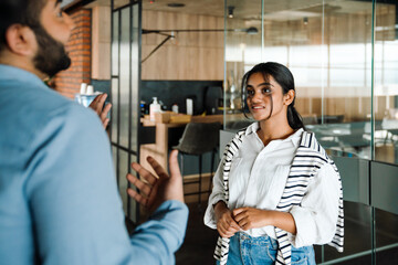 Indian business people discussing project details while standing in office lobby