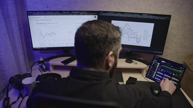 Businessman works for PS in home office. A man keeps notes, looks at graphics on a computer and tablet at home. High quality 4k footage