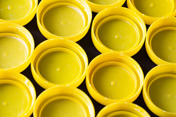 Plastic bottle caps background. Collecting bottle caps texture. Yellow color plastic texture. Stacked pile of caps. Soda bottle PET trash.