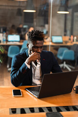 Portrait of successful businessman in office. Young smiling man using the laptop..