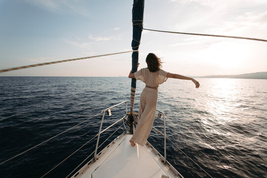 Woman with arm raised standing on sailboat