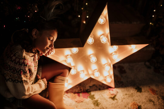 Girl with eyes closed leaning head on star shape light