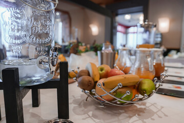 Closeup of drink dispenser with various fresh fruits in metallic basket kept on table in luxury hotel, luxury travel concept breakfast.