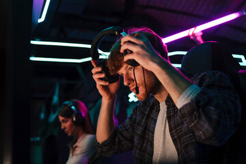 Gamer putting on headphones while playing video game in cybersport club © Drobot Dean