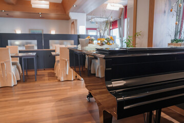 Black shiny grand piano in illuminated restaurant of luxury hotel, luxury travel concept