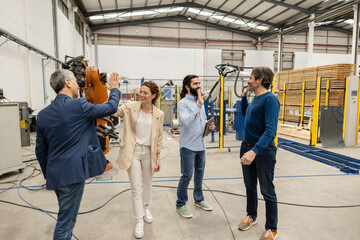 Happy engineers giving high-five to each other in robotic industry