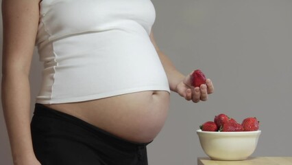 Pregnant woman eating strawberries - Powered by Adobe