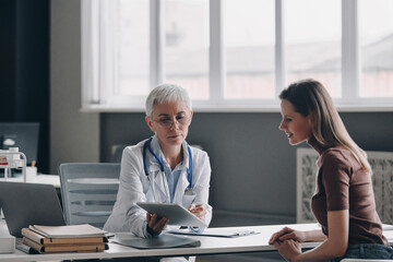 Confident female doctor discussing prescription with patient while sitting at the medical office