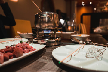 Closeup of fresh meat served on a plate at table in restaurant. Delicious luxury meat fondue.
