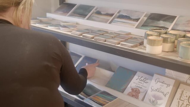 A retail worker stocks the shelves in a shop with gift cards. Shot on the Isle of Lewis, part of the Outer Hebrides of Scotland.