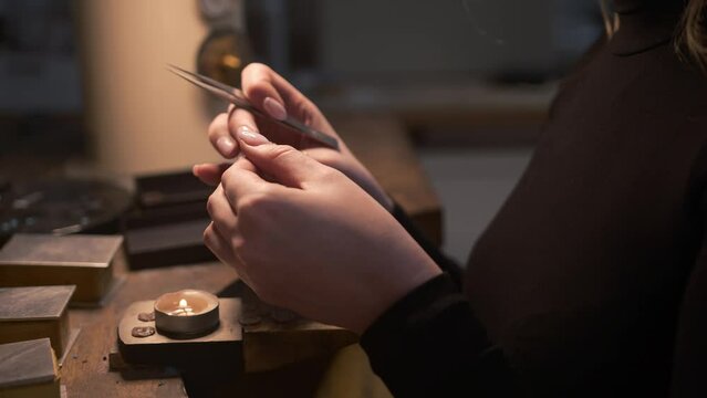 Static close up of a female jeweller making a silver metal mould over a candle to be made into a necklace. Shot on the Isle of Lewis, part of the Outer Hebrides of Scotland.