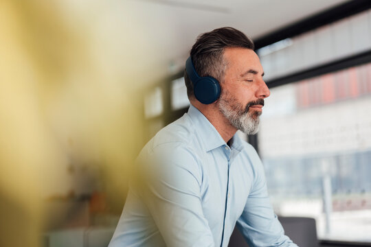 Businessman wearing wireless headphones listening to music