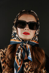 A woman in a leopard scarf and fur coat on a dark background