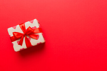 Top view photo of valentine day decorations gift box with red ribbon bow on colored background. Holiday gift boxes with top view