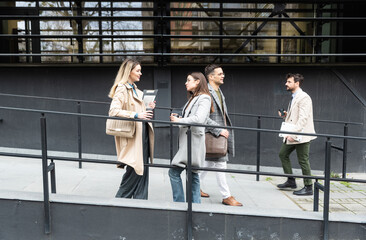 A regular day for working people standing talking walking in front of the office building where they work going to and from workplace. Businesspeople between staff meetings outdoor.