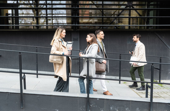 A regular day for working people standing talking walking in front of the office building where they work going to and from workplace. Businesspeople between staff meetings outdoor.