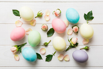 Happy Easter. Easter eggs on colored table with yellow roses. Natural dyed colorful eggs background top view with copy space