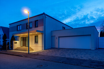 Germany, Bavaria, Street light glowing in front of modern suburban house at dusk