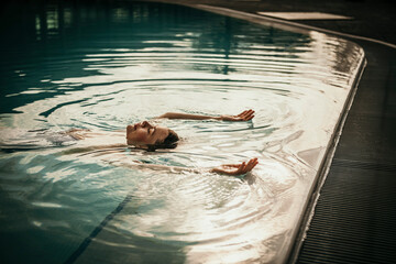 Woman with arms raised floating in swimming pool