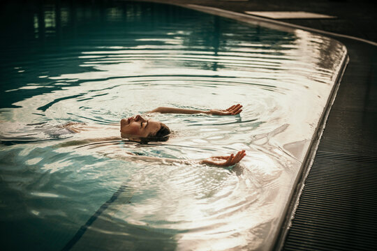 Woman with arms raised floating in swimming pool