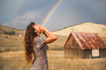 Optical illusion of rainbow coming out from mouth of woman standing in field