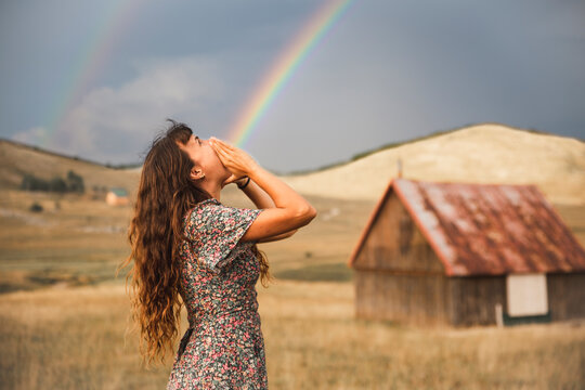 Fototapeta Optical illusion of rainbow coming out from mouth of woman standing in field