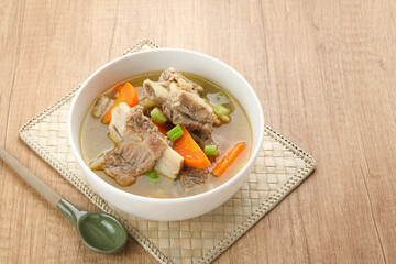 Sop Iga (Beef ribs soup) made from ribs, carrots, leeks.  Served in white bowl. Indonesian food