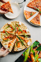 Traditional Italian pizza, vegetables, ingredients on a light background.Top view. a piece of pizza in the hand.Festive table. company of friends