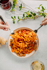 Italian pasta, tomato sauce. Two female hands in the frame, girls eat pasta, hold forks in their hands, top view, Italian cuisine.