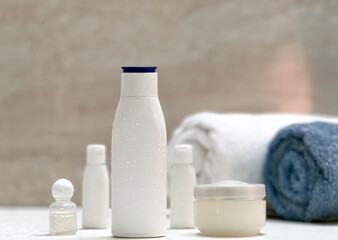 Closeup of toiletries bathroom setup in a isolated white tiles background with copy space for inscription. Towl, dispensers, comb, toothbrush and moisturizer. Bathroom interior. 