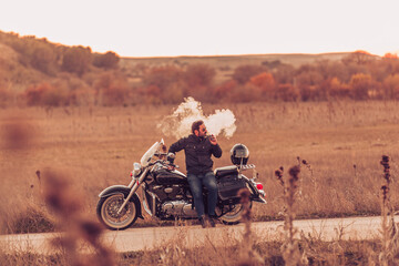 Motorcyclist with cigar standing on the road