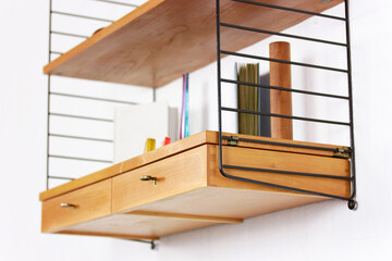 a mid century String Shelf with drawers original from the 60s mounted on a white wall with books...