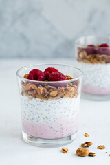 Raspberry chia seed parfait made with granola and berries in a cups.