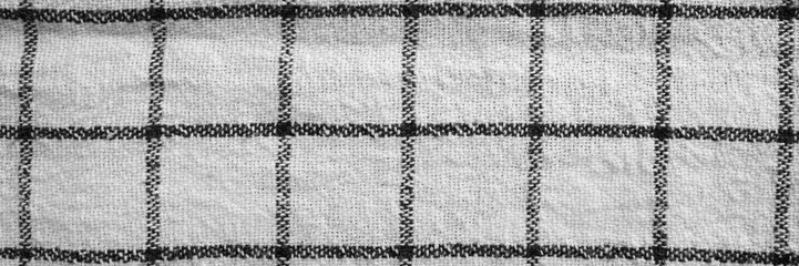 Classic black and white checkered kitchen towel texture banner. Fabric textile background with visible weave and thread detail. Top view panoramic web header. Wide screen wallpaper