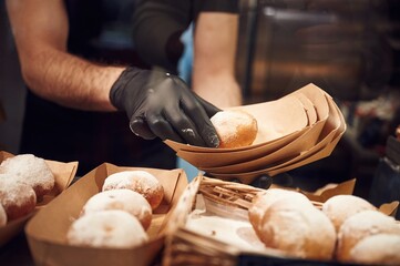 Delicious donuts. Man is taking food in the workspace. Conception of sweet desserts