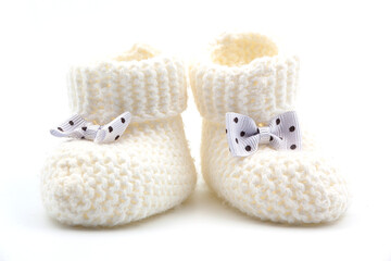 Fototapeta na wymiar White knitted baby booties with bows on a gray isolated background