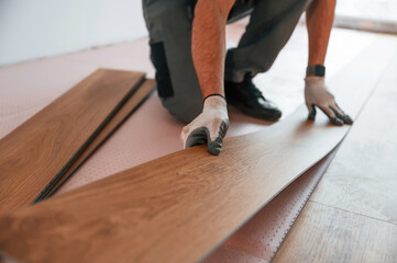 Close up view. Man is installing new laminated wooden floor