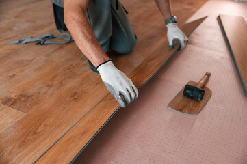 Close up view. Man is installing new laminated wooden floor