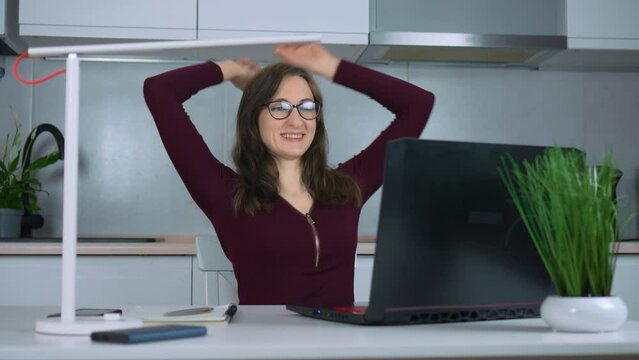 Smiling businesswoman or student in glasses finished computer work, stretching relaxing seated at workplace feeling stress relief, satisfied by project accomplishment, task done in time. Busy worker