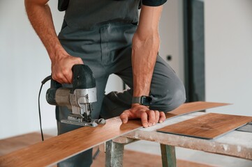 On the table. Cutting planks by the drill. Man is installing new laminated wooden floor