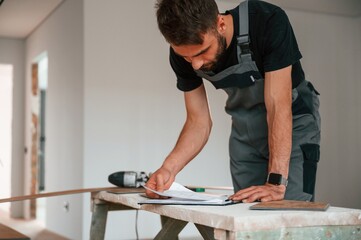 Reading the information. Man is installing new laminated wooden floor