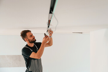 Installing lighting equipment on the ceiling. Man is working indoors at domestic room