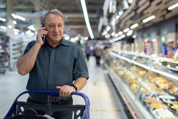 Elderly man consulting on mobile phone while shopping at grocery store