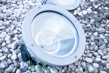 Modern metal spotlight  lamp for outdoor use of circular shape recessed with gravel used to...